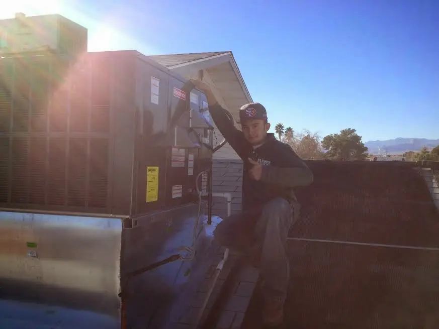 HVAC technician performing Air Duct Cleaning on a rooftop unit in McComb